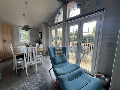 A dining room with a table and chairs at Holly Blue - Cosy wooden lodge, Kippford