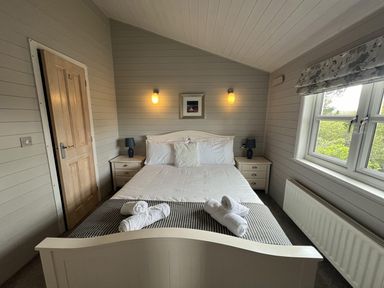 A bedroom with a bed and bedside tables at Holly Blue - Cosy wooden lodge, Kippford