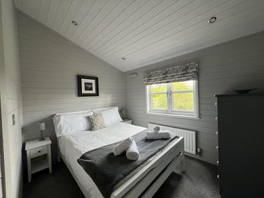 A bedroom with a bed and nightstand at Holly Blue - Cosy wooden lodge, Kippford