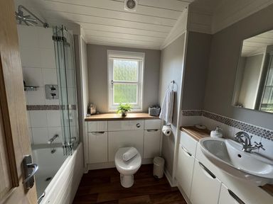 A bathroom with a bathtub, sink, and toilet at Holly Blue - Cosy wooden lodge, Kippford