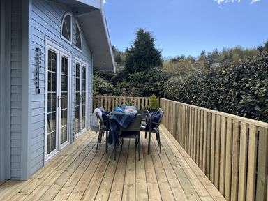 A deck with a table and chairs at Holly Blue - Cosy wooden lodge, Kippford