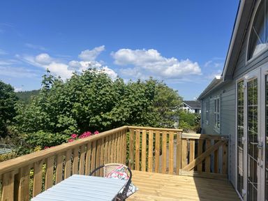 A decking area with a table and chair at Holly Blue - Cosy wooden lodge, Kippford