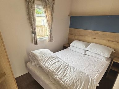 A bedroom with a bed and window at Caravan Sleeps 5 - Decking, Parking, Pet Friendly, Blackpool