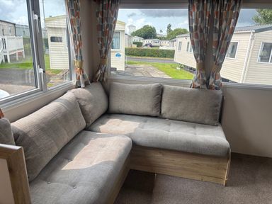 A living room with a sofa near a window at Caravan Sleeps 5 - Decking, Parking, Pet Friendly in Blackpool