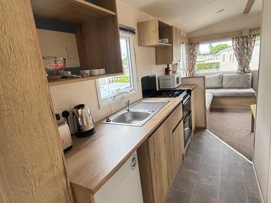 A kitchen with a sink, cooker, and microwave at Caravan Sleeps 5 - Decking, Parking, Pet Friendly in Blackpool