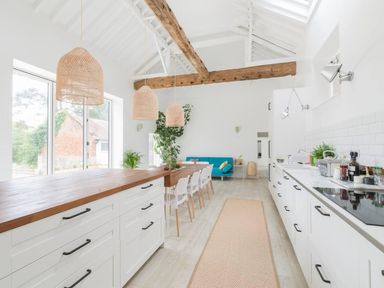 A kitchen with an island and dining setup at Simple Coastal Luxury near Southwold
