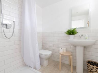 A bathroom with a shower, sink, toilet, and stool at Simple Coastal Luxury near Southwold