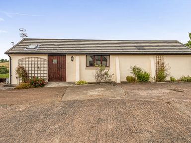 An exterior view of a property with a door and windows at The Shippon, Breathtaking Views, Private Hot Tub, Winkleigh