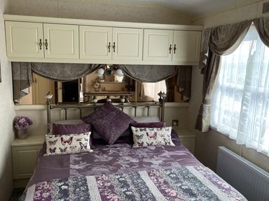 A bedroom with a bed and decorative cushions at Chalet Sleeps 4 Near Cymyran Beach Caergeiliog
