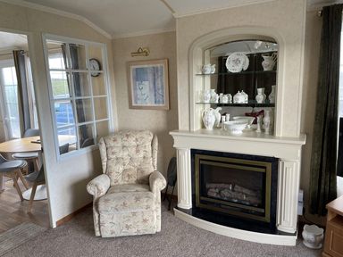 A living room with an armchair and fireplace at Chalet Sleeps 4 Near Cymyran Beach Caergeiliog