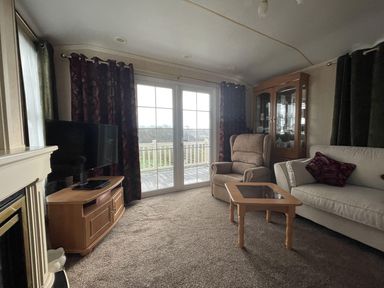 A living room with a television and sliding door at Chalet Sleeps 4 Near Cymyran Beach in Caergeiliog