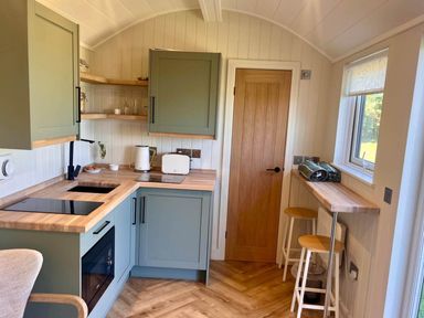 A kitchen with green cabinets and wooden countertops at Peaceful Shepherd Hut near Clovelly