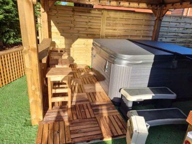 An outdoor area with a hot tub and wooden stools at Cabin Sleeps 4 with Hot Tub and Parking Near Wilberfoss