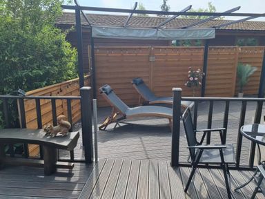 An outdoor area with lounge chairs and a table at Cabin Sleeps 4 with Hot Tub and Parking Near Wilberfoss