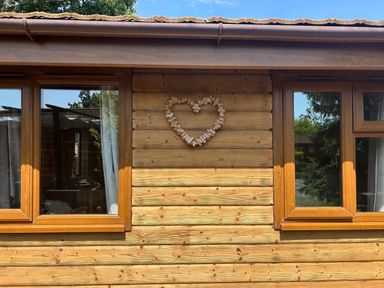 A wooden exterior wall with windows and a heart decoration at Cabin Sleeps 4 with Hot Tub and Parking near Wilberfoss