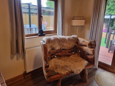 A living room with a wooden armchair and a radiator at Cabin Sleeps 4 with Hot Tub and Parking near Wilberfoss