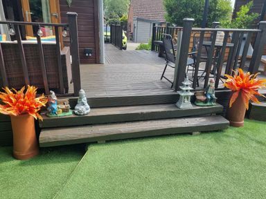An outdoor area with steps leading to a deck, flower pots, and decorative statues at Cabin Sleeps 4 with Hot Tub and Parking near Wilberfoss
