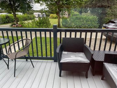 A deck with chairs and a table overlooking a yard at the property in an outdoor setting