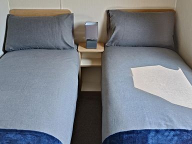 A bedroom with two beds and a lamp at Golden Sands 3-Bed Caravan, Parking and Pet Friendly in Towyn