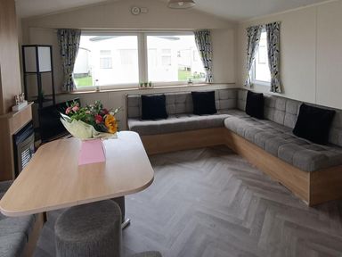 A living room with a corner sofa and a table at Golden Sands 3-Bed Caravan, Parking and Pet Friendly in Towyn
