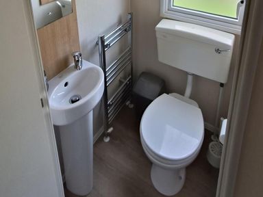A bathroom with a sink, toilet, and towel rail at Golden Sands 3-Bed Caravan, Parking and Pet Friendly, Towyn