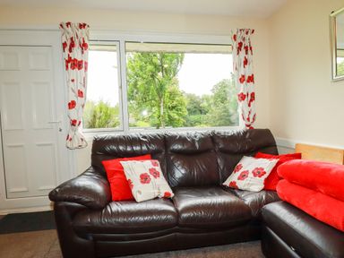 A living room with a sofa and window view at Villa 12 near Camelford