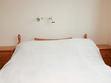 A bed with a blanket and a lamp at Villa 12 near Camelford