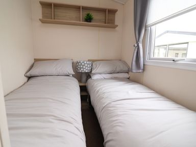 A bedroom with two beds and a lamp on the shelf at B54