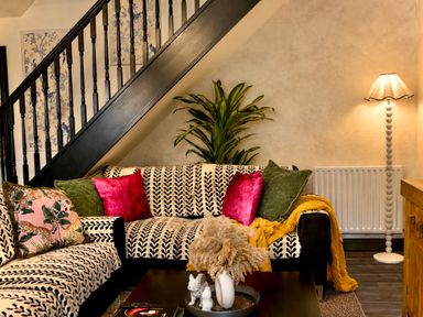 A living room with a sofa and staircase at Muddy Boots – La Petite Mews in Kirby Stephen