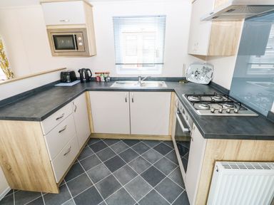 A kitchen with cabinets and a gas stove at Seascape in Haverfordwest