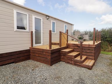 An exterior view of a mobile home with a wooden deck near Little Haven
