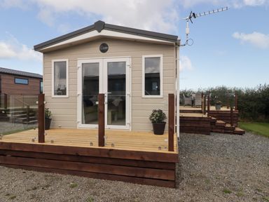 A cabin with a wooden deck and glass railing at Seascape near Little Haven