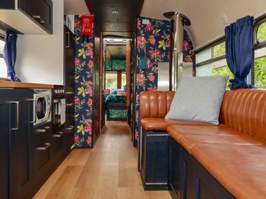 A living room with a couch and kitchen area at Honey Bee Bus in Menheniot