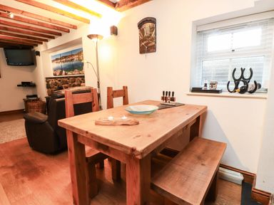 A dining table with wooden chairs at 2 bed in Criccieth