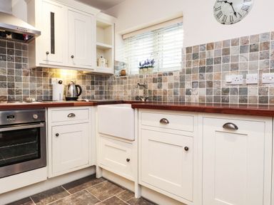A kitchen with cabinets and a sink at 2 bed Criccieth
