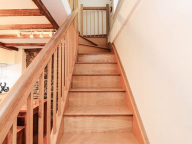 A staircase with wooden steps and railing at 2 bed Criccieth