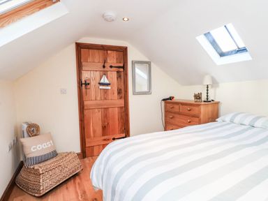 A bedroom with a bed and a wooden dresser at 2 bed Criccieth