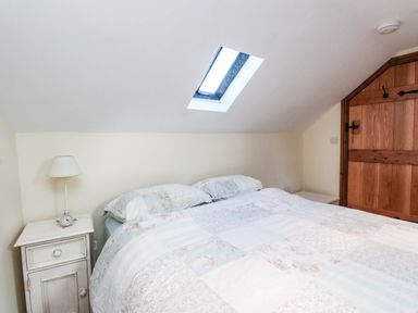 A bedroom with a bed and bedside table at 2 bed Criccieth