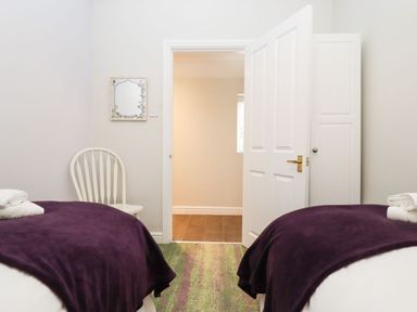 A bedroom with two beds and a chair at Peewit Barn in Moreton-in-Marsh