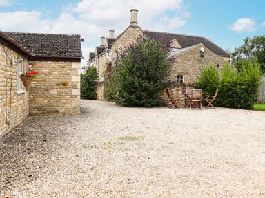 An outdoor area with gravel and wooden furniture at Peewit Barn Moreton-in-Marsh