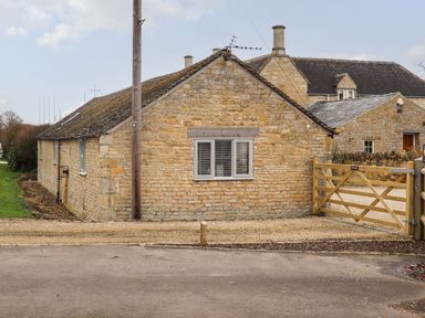 A stone building with a window and gate at Peewit Barn in Moreton-in-Marsh