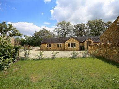An outdoor area with a stone building and gravel driveway at Peewit Barn in Moreton-in-Marsh