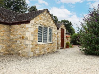 A stone cottage with gravel pathway and potted plants at Peewit Barn Moreton-in-Marsh