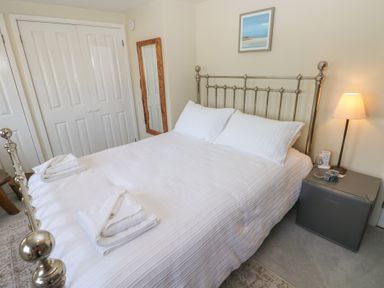 A bedroom with a bed, side table, lamp, and mirror at Hafan y Tyddyn 