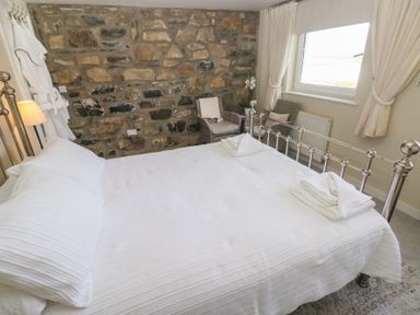 A bedroom with a bed and chair at Hafan y Tyddyn