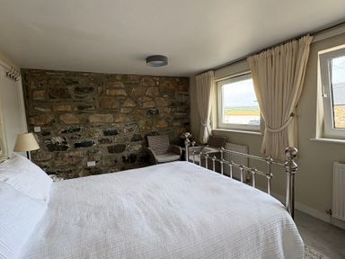 A bedroom with a bed and windows at Hafan y Tyddyn in Newport, Pembrokeshire