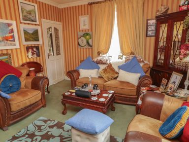 A living room with sofas, a coffee table, and paintings at Bruckless Rest Fine Country Dining B&amp;B, Bruckless