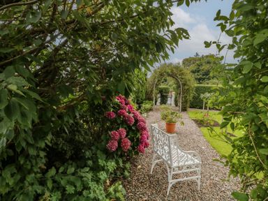 A garden with a pathway, flowers, and a bench at Bruckless Rest Fine Country Dining B&amp;B Bruckless