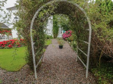 A garden with an archway and gravel path at Bruckless Rest Fine Country Dining B&amp;B, Bruckless