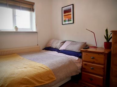 A bedroom with a bed, nightstand, and window at Ty Marlyn in St Davids